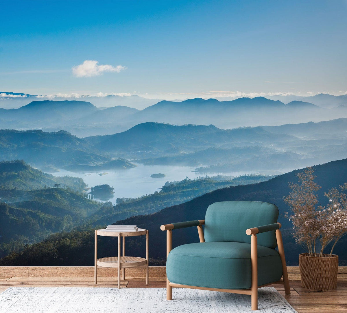 Serene blue misty mountain mural wallpaper for living room with teal armchair on wooden flooring.