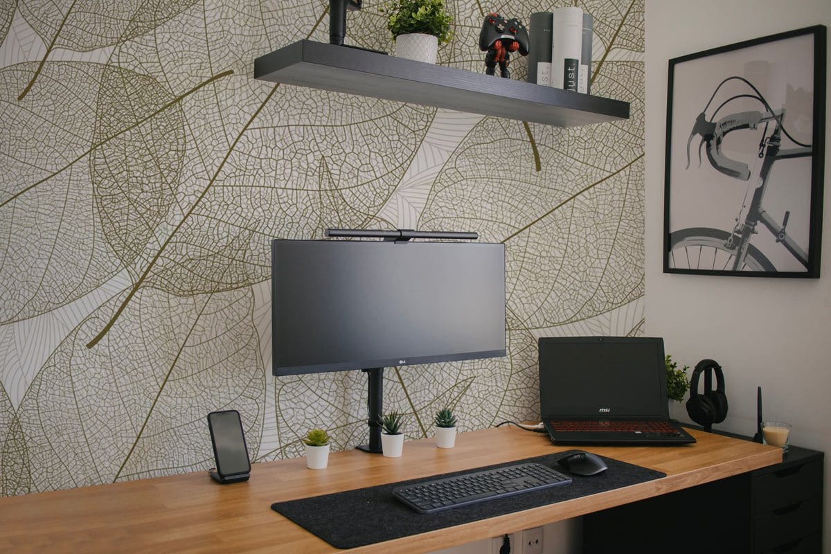 Elegant beige leaf vein wallpaper in home office with wooden desk, floating shelf, and minimalist decor.