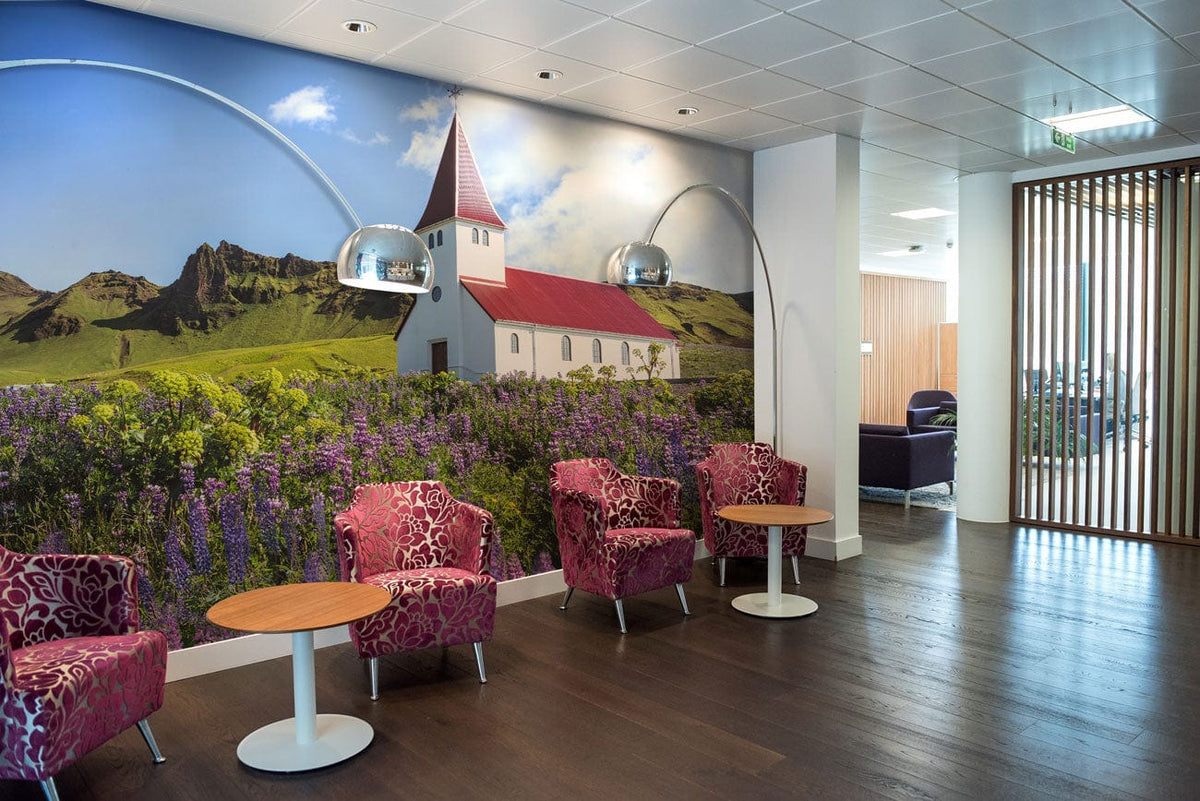 Idyllic Countryside Church Mural Wallpaper with pink chairs, round tables, wooden flooring in bright lounge.