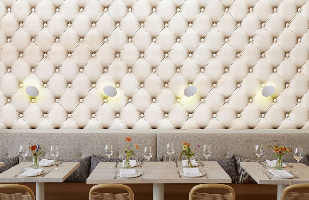Luxurious quilted cream wallpaper in stylish dining room, elegant seating, sophisticated interior design.