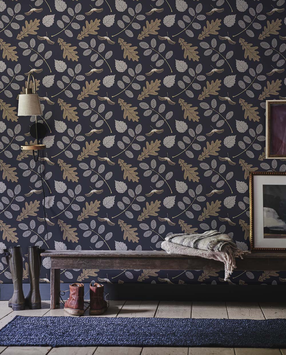 Botanical leaf pattern wallpaper in navy and gold with bench, textured rug, grey floor tiles.