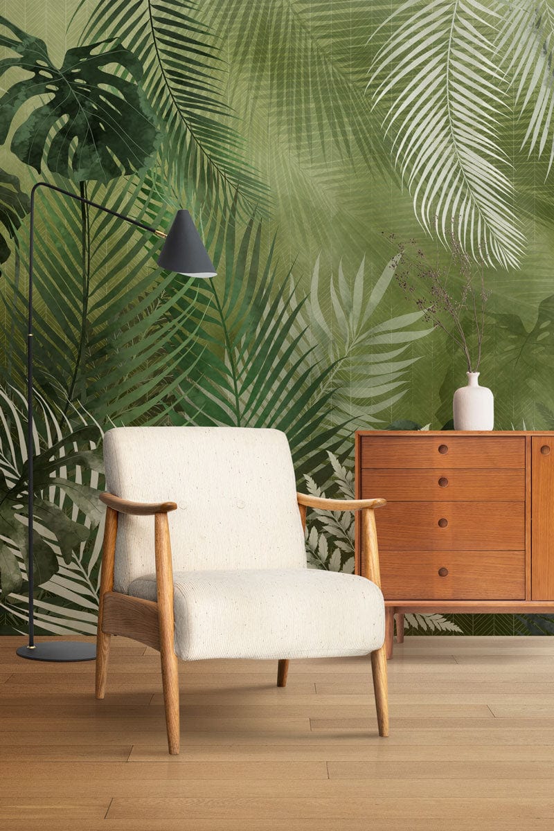 Tropical Green Jungle Foliage Wallpaper with botanical pattern, armchair, wooden cabinet, light wood flooring.