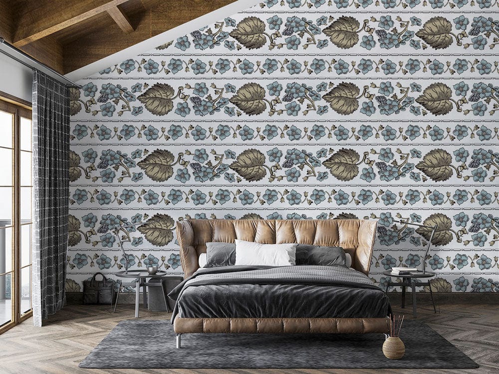 Vintage floral wallpaper with blue, olive design; brown leather bed, large windows, wooden flooring in bedroom.
