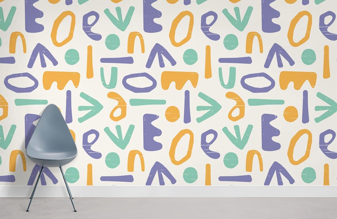 Playful Pastel Geometric Wall Mural with grey chair, vibrant abstract pattern wallpaper, modern decor.
