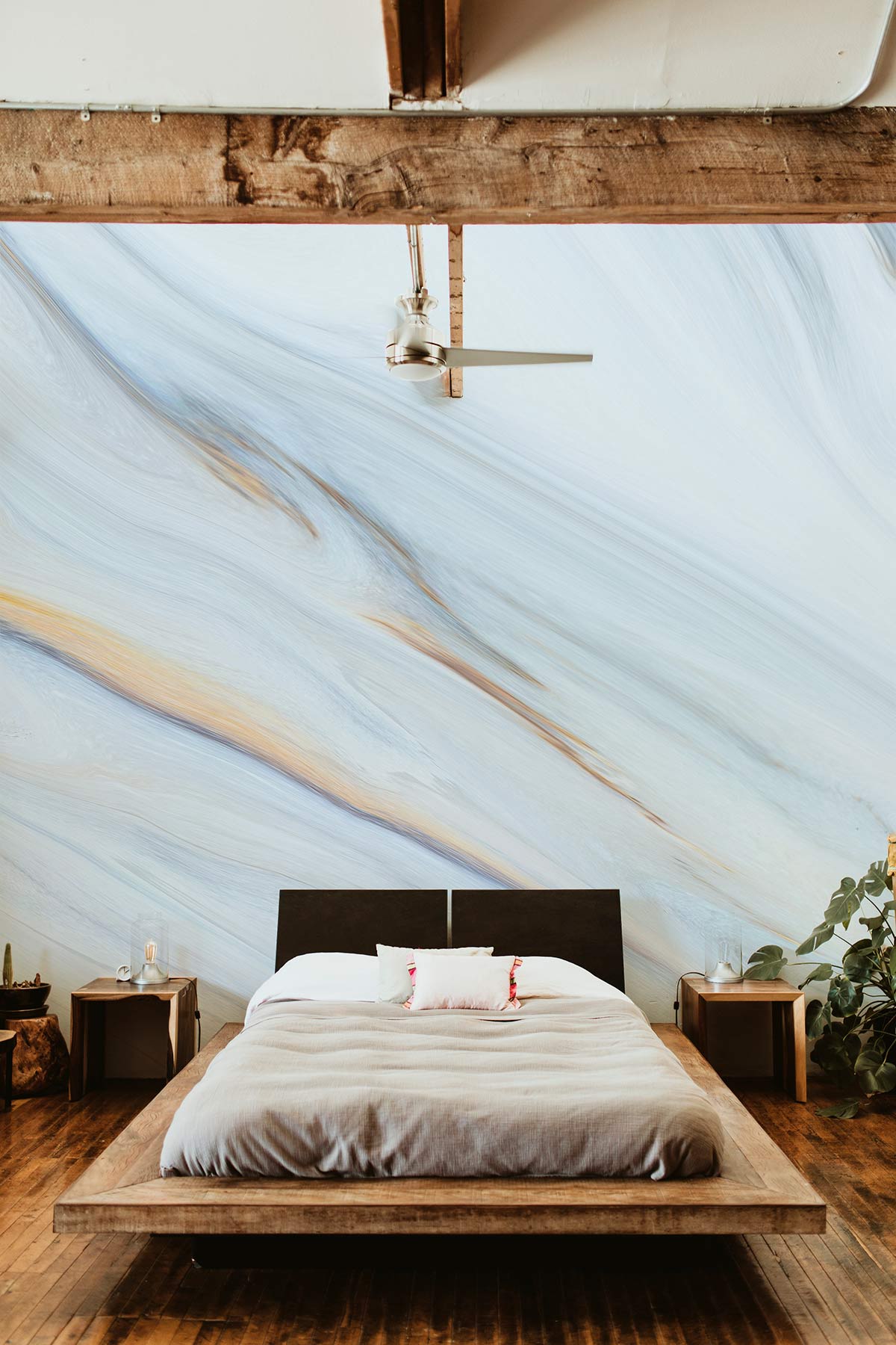 Elegant marble effect blue and beige wallpaper mural in modern bedroom with wooden flooring, ceiling fan.