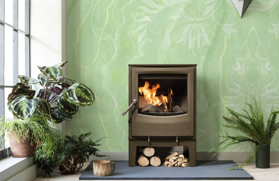 Elegant mint green floral damask wallpaper in living room with stove and leafy plants.