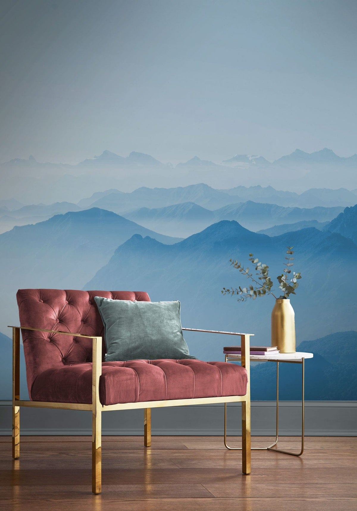 Tranquil Blue Mountain mural in serene room with plush pink chair, wooden flooring, metal side table.