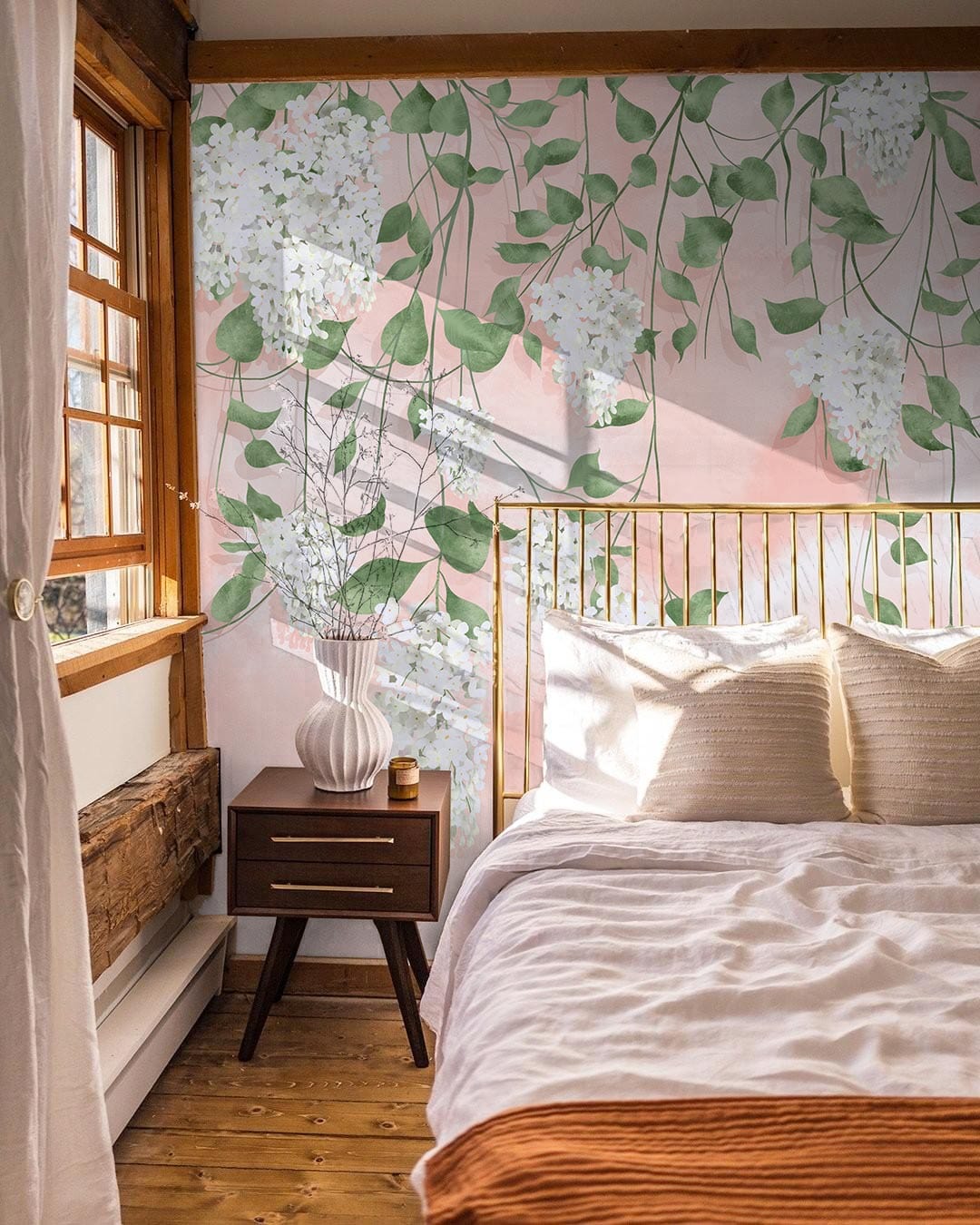 Elegant floral wallpaper in pastel peach tones, wooden bed frame, cosy bedroom setting, warm sunlight.