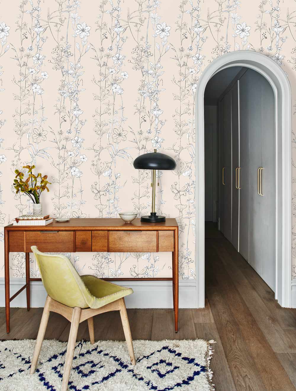 Elegant beige floral wallpaper, wooden desk, yellow chair, grey arch doorway, wooden flooring, patterned rug.