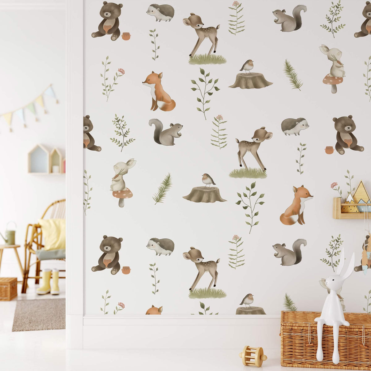 Charming woodland wallpaper in nursery with pastel forest animals; wicker chair decor and plush toys.