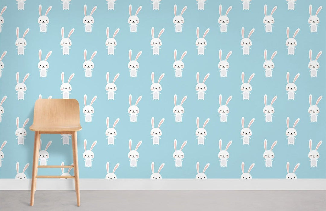 Charming Pastel Blue Bunny Wallpaper for Kids' Room with Wooden Stool and Grey Flooring.