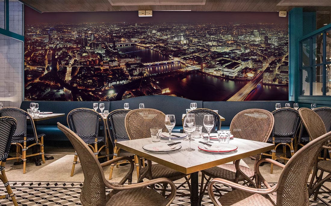 London night skyline wallpaper in chic restaurant with rattan chairs, industrial decor, and tiled flooring.