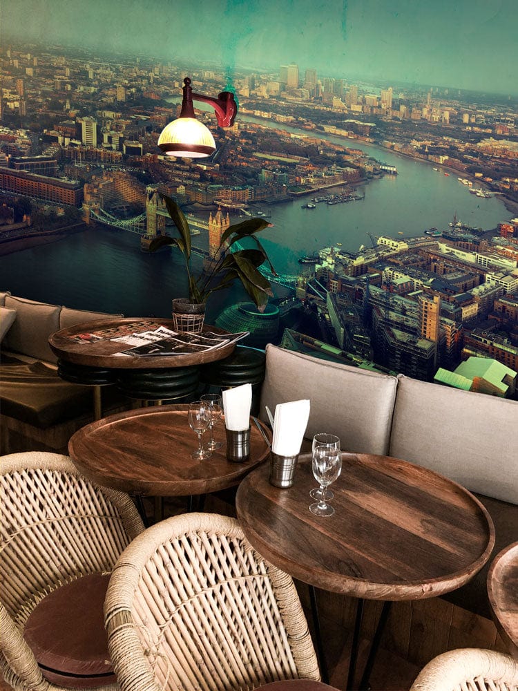 Panoramic mural with London skyline, rustic wood tables, wicker chairs, cosy café setting, soft lighting.