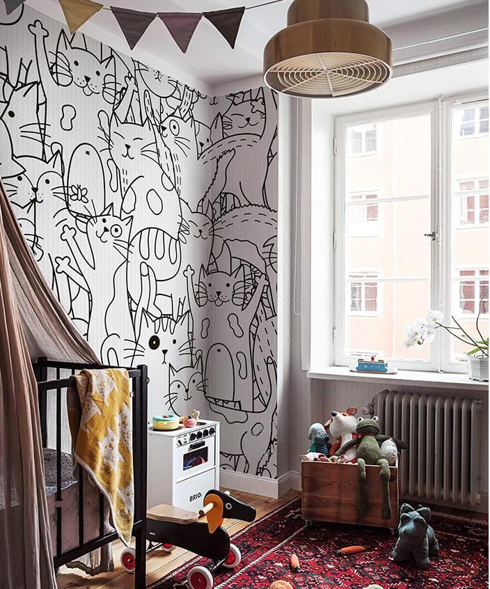 Children's room with Monochrome Cats Patterned Wallpaper, vintage toy box, red oriental rug, natural light.