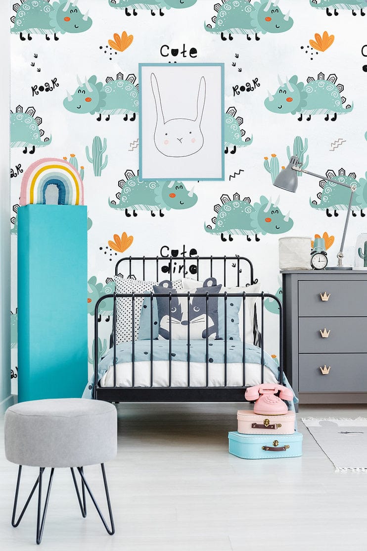 Adorable green dinosaur mural in child's room with grey dresser, black bed, soft stool, wooden floor.