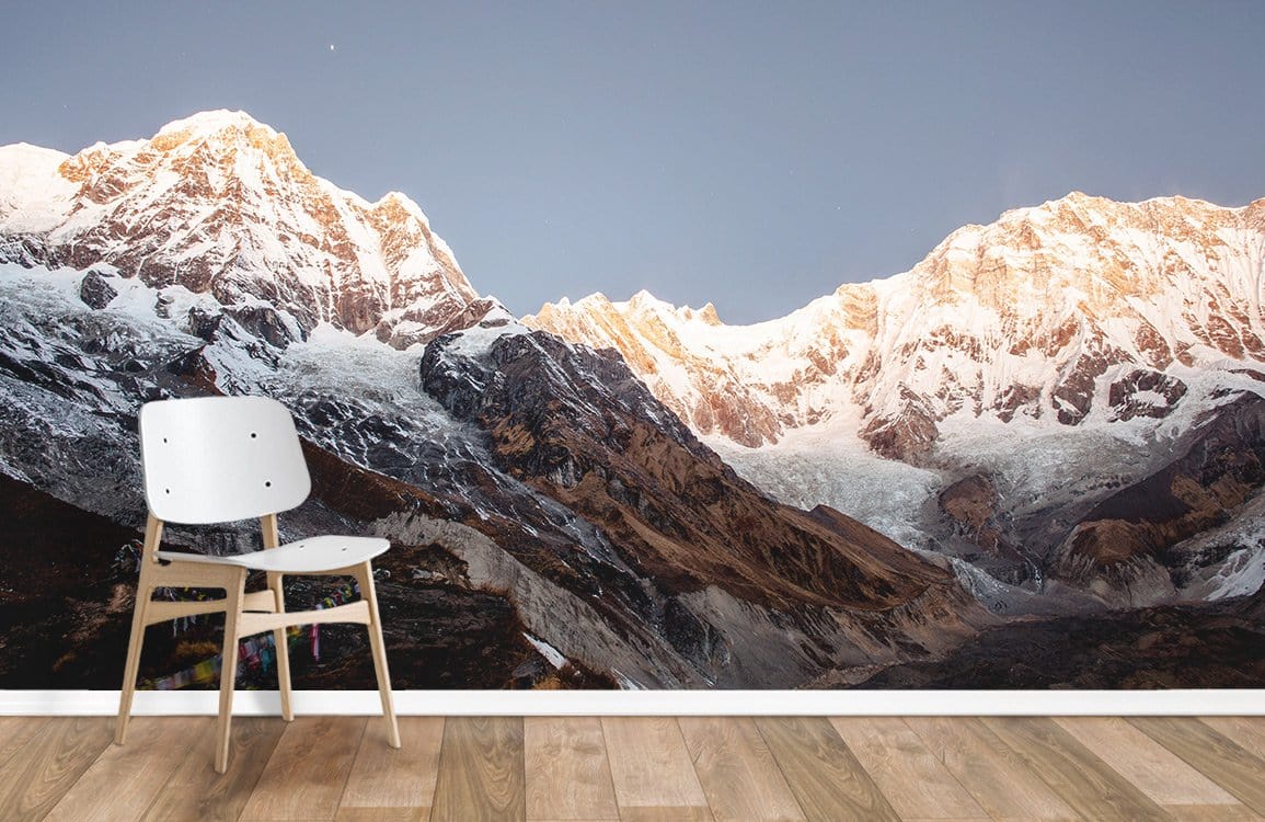 Majestic Mountain Sunset Mural Wallpaper in living room, white chair, wood flooring, serene Himalayan landscape.