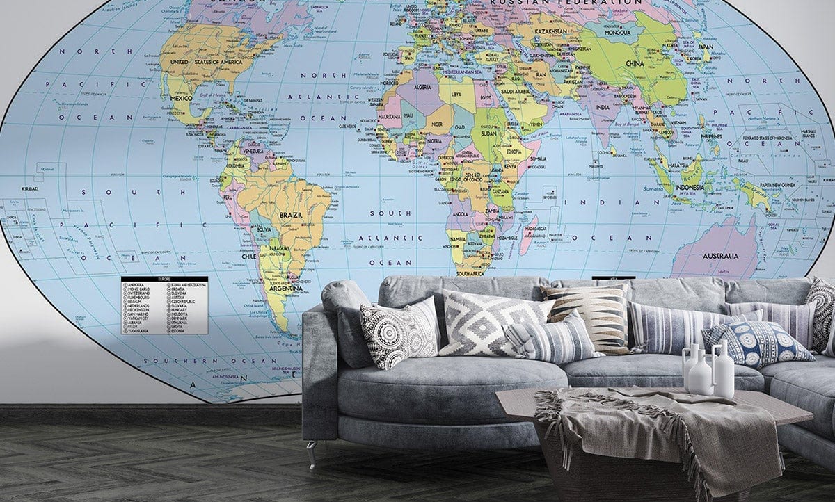 Vintage world map mural wallpaper in living room, grey sectional sofa, chevron wood flooring.