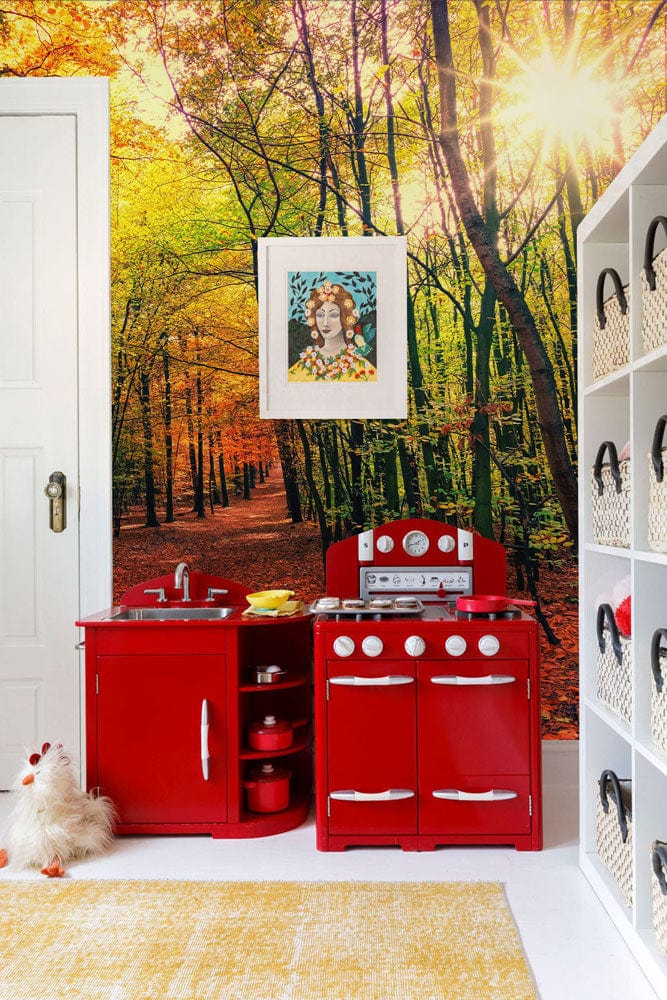 Enchanting Autumn Forest Path wallpaper, white shelving, red play kitchen, vibrant children's room decor.
