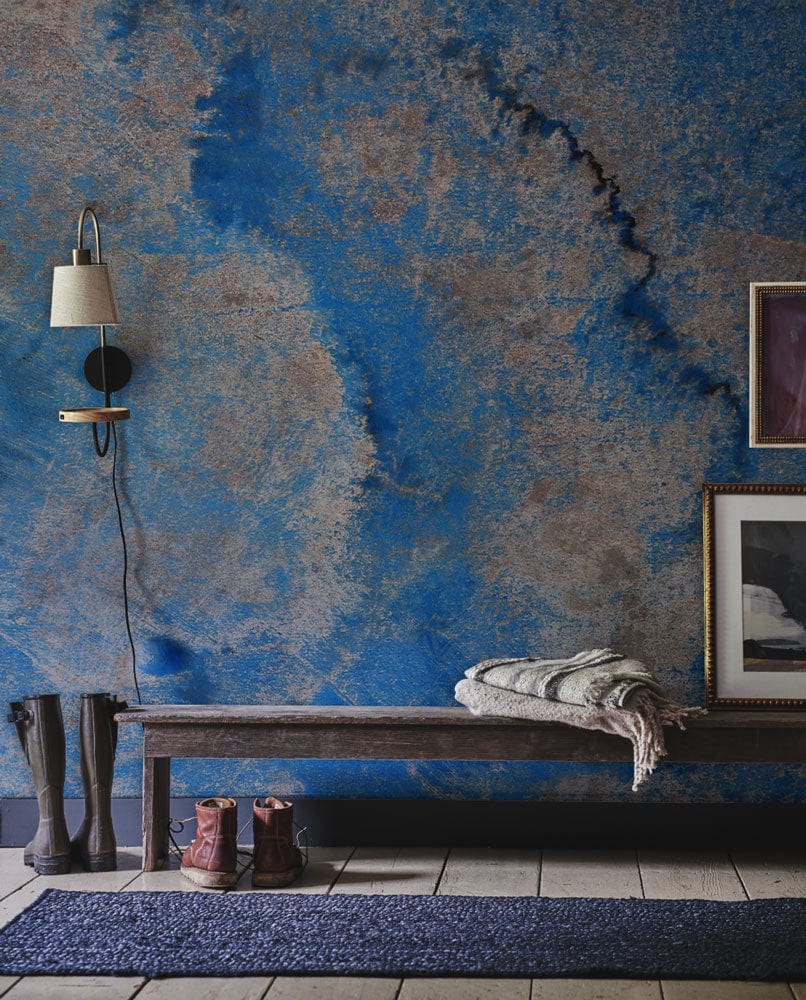 Abstract blue textured mural wallpaper with rustic bench, modern wall lamp, and framed artwork accents.