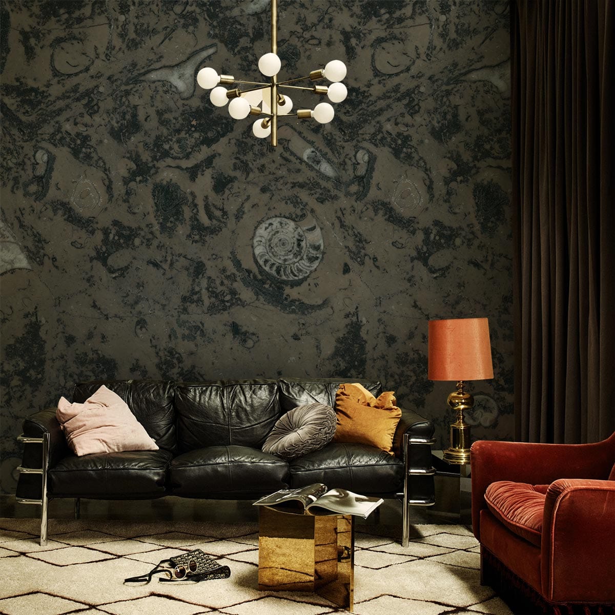 Dark Fossil Swirl wallpaper, natural earth tones; black leather sofa, gold table, modern chandelier.