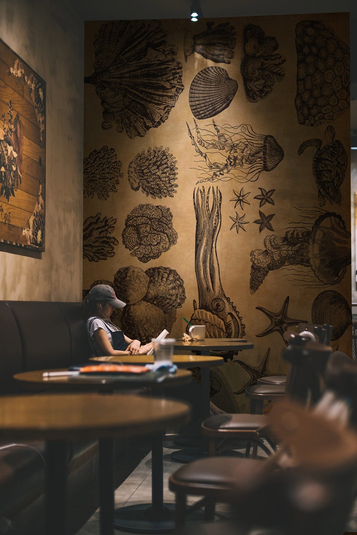 Vintage sepia marine mural in cosy café with brown seating, nautical decor, wooden tables, dim lighting.