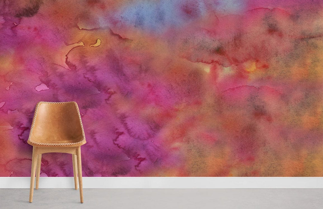 Vibrant watercolour floral mural wallpaper in pink, orange, blue tones with a brown leather chair.