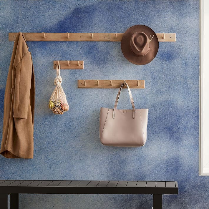 Serene Sky Blue Watercolour Wallpaper with wooden hooks, grey bench, and bag in modern hallway.