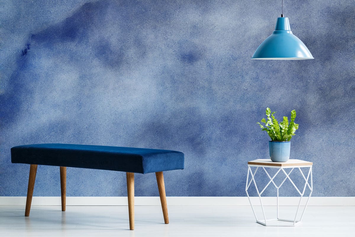 Serene sky blue watercolour wallpaper in modern room with dark blue bench, geometric table, pendant lamp.