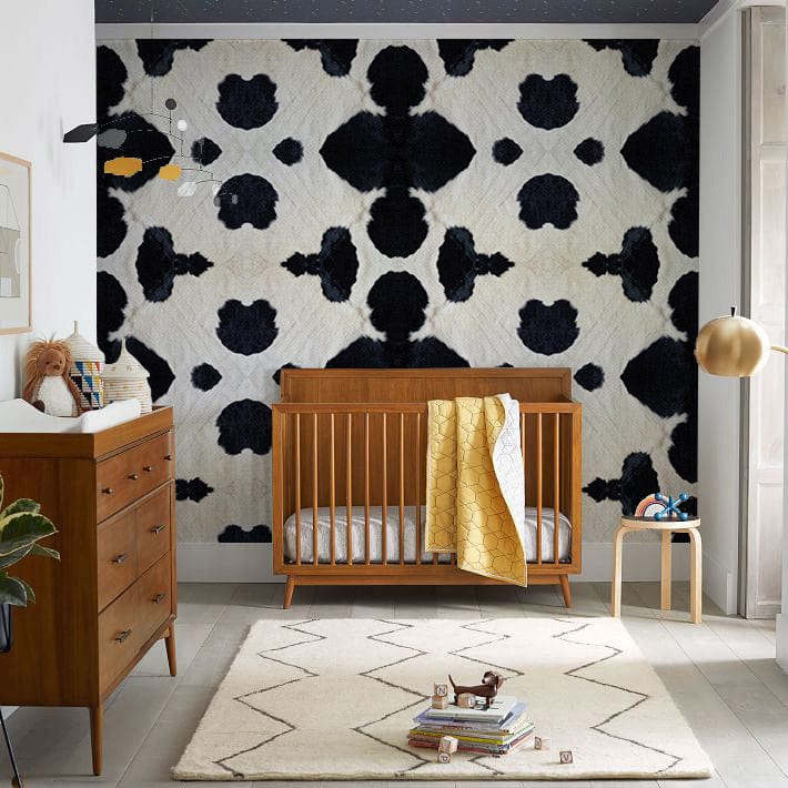 Monochrome Abstract Pattern Wall Mural in nursery, featuring wooden crib, grey rug, and modern lamp.