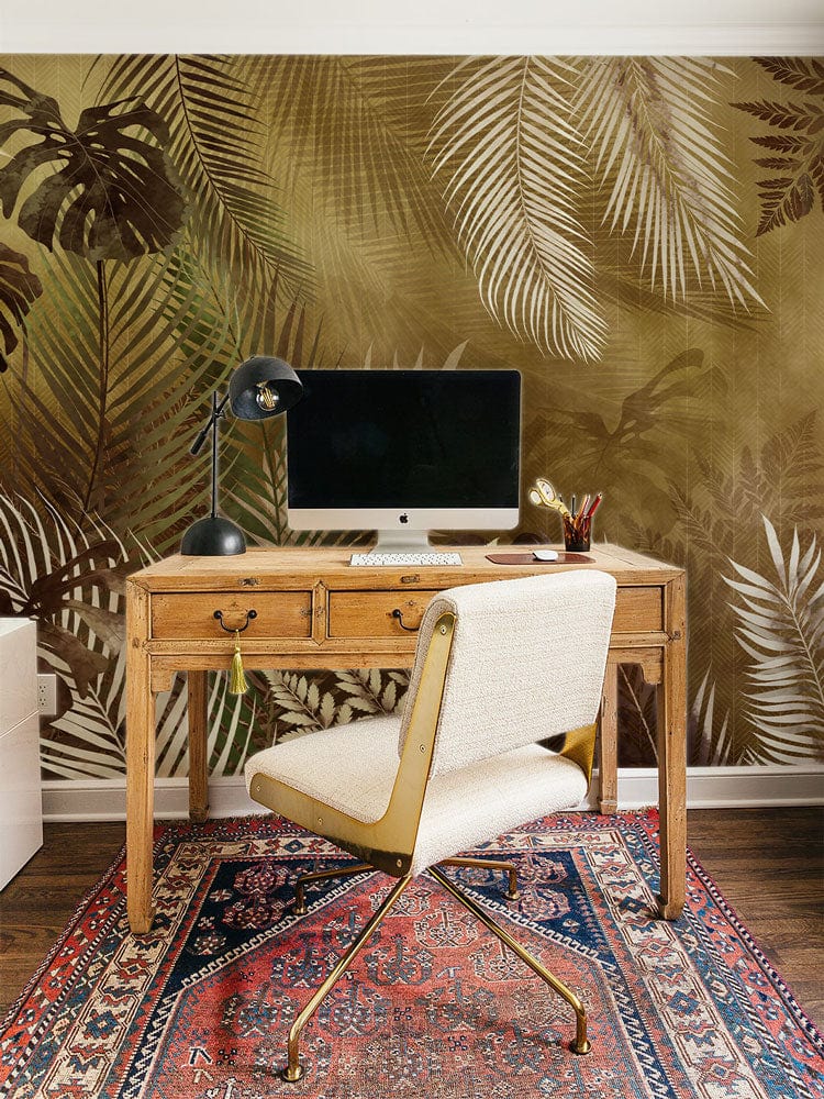 Home office with vintage tropical foliage wallpaper, wood desk, cream chair, patterned rug on wooden floor.