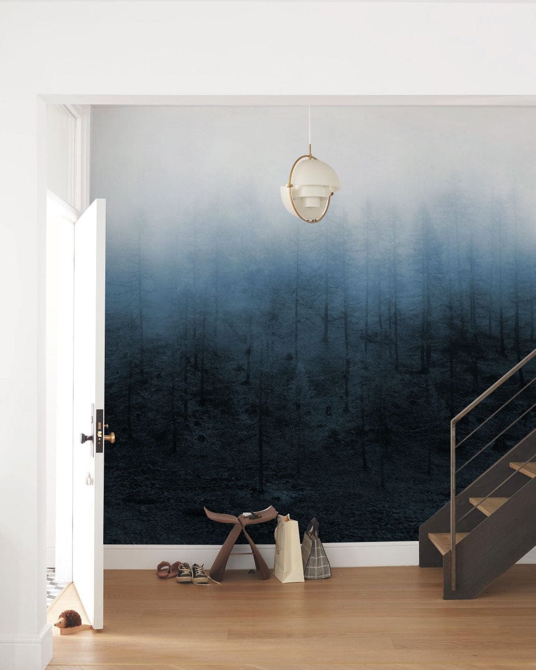 Misty Forest Scene Mural Wallpaper in blue, white walls, pendant light, wooden flooring in hallway.