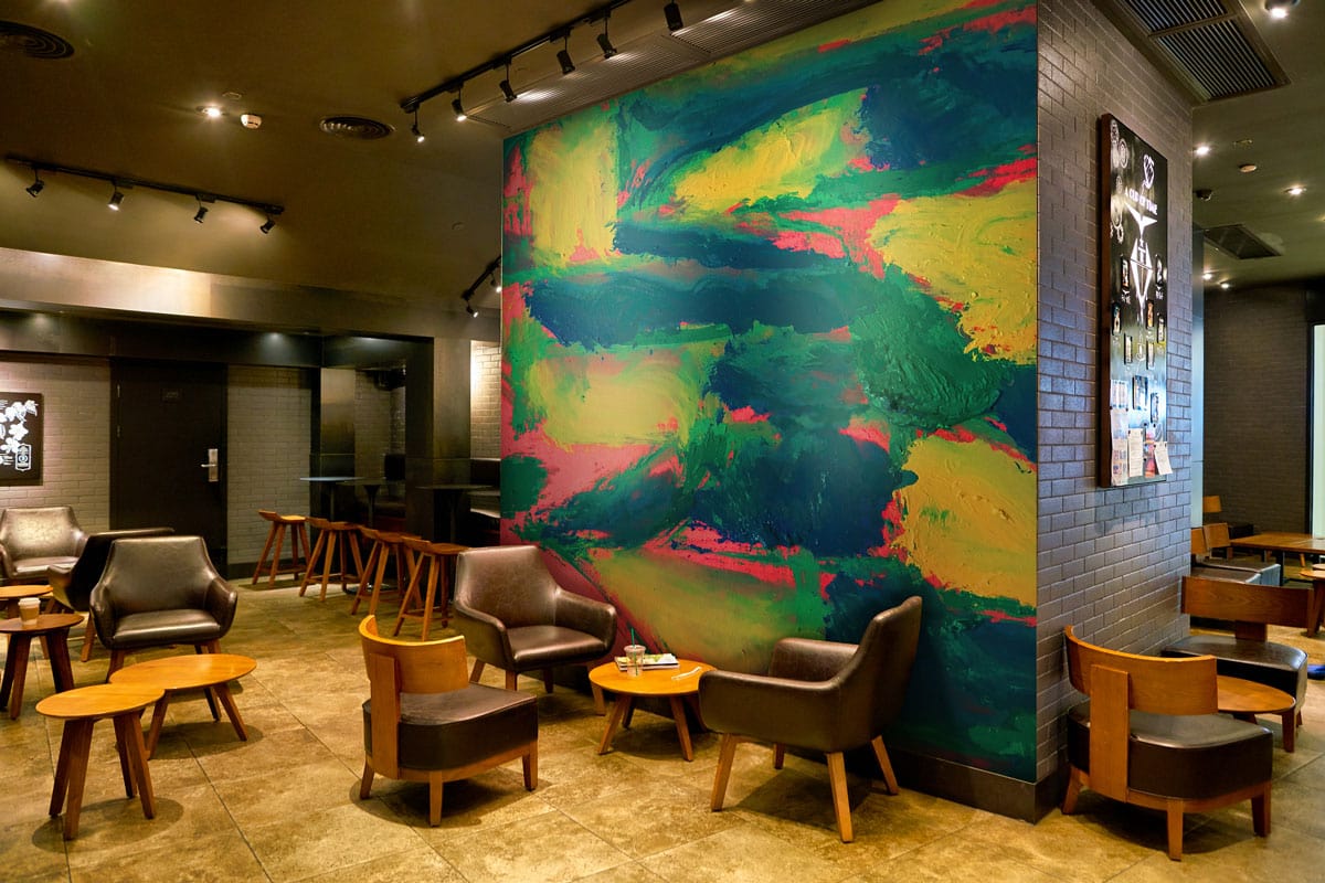 Vibrant abstract neon brushstroke pattern wallpaper in cafe with dark leather chairs, wooden tables, tiled floor.