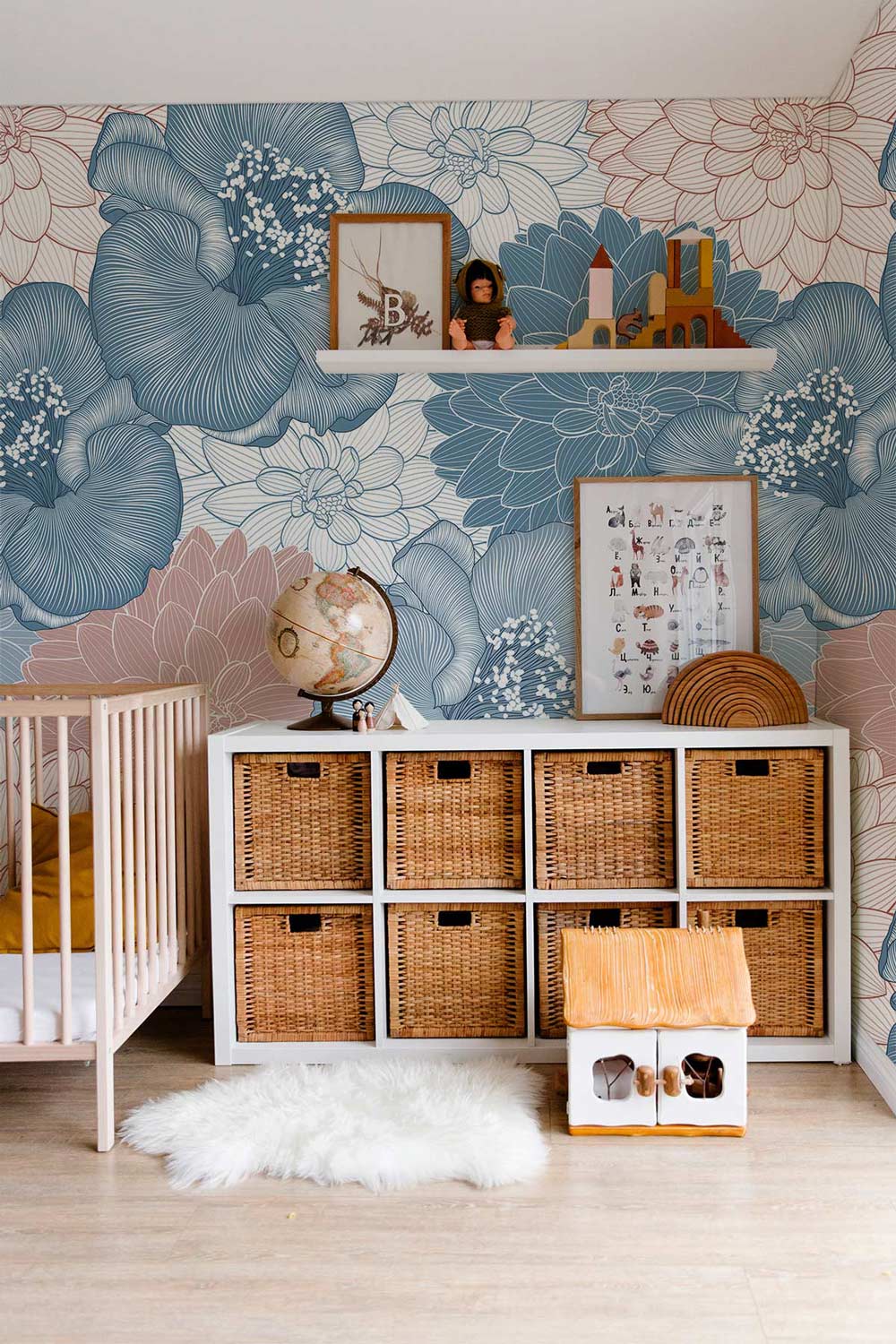 Vintage floral wallpaper in nursery, wicker storage, wooden cot, light wood flooring, retro decor.