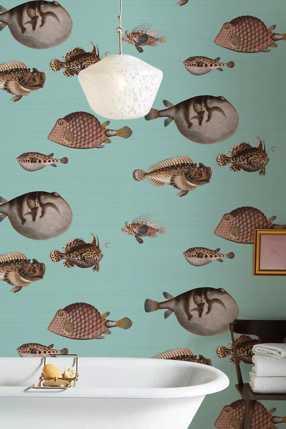 Vintage turquoise fish pattern wallpaper with white bathtub, pendant light, and framed picture in bathroom.