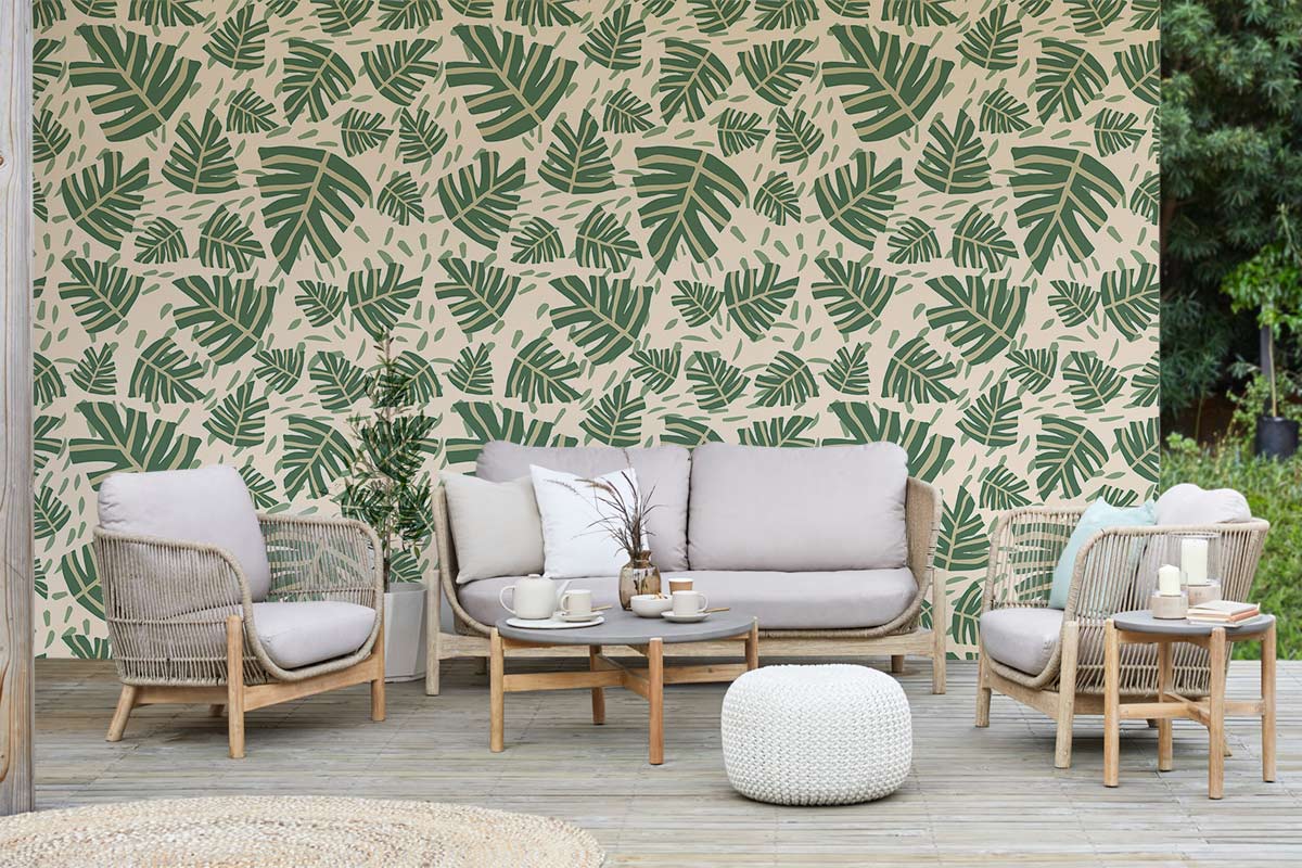 Tropical Green Leaf Print Wallpaper, botanical decor with rattan furniture, neutral sofa, wooden flooring.