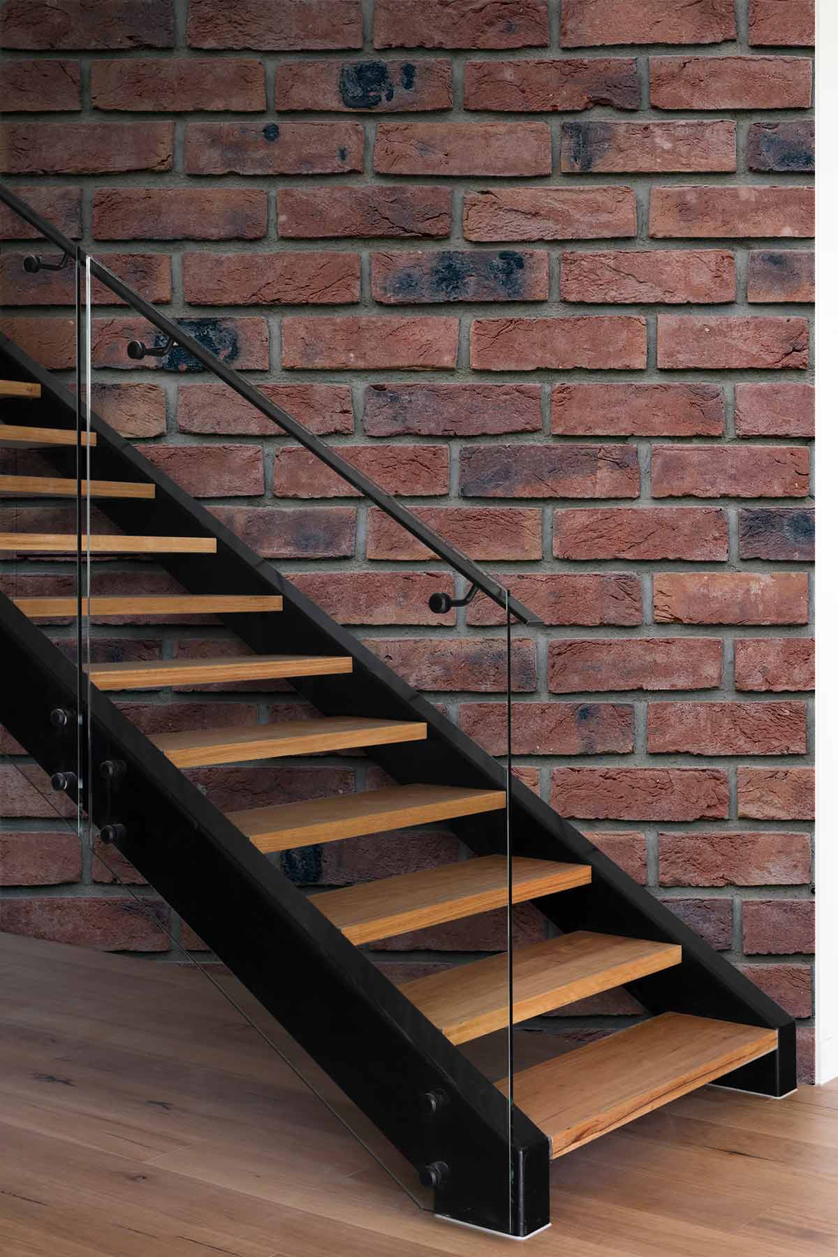 Classic red brick wall wallpaper with wooden staircase, glass railing, and wooden flooring in a hallway.