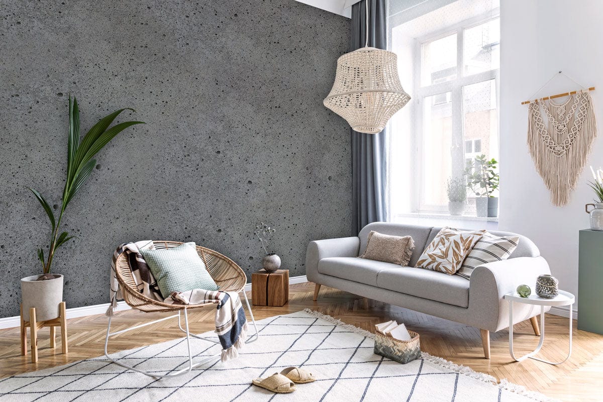 Industrial grey concrete effect wallpaper with modern minimalist decor, grey sofa, wicker chair, wooden flooring.