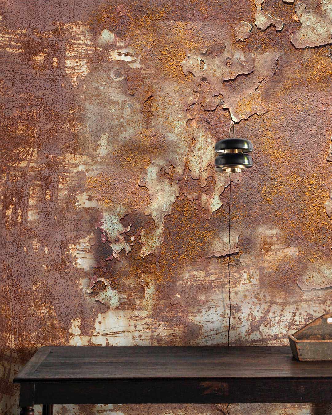 Industrial rust brown vintage mural wallpaper with weathered texture, brown table, and pendant light fixture.