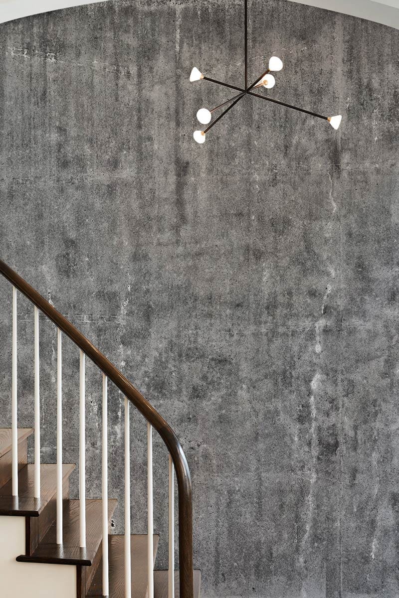Industrial grey concrete texture wallpaper, modern pendant light, wooden staircase, urban chic interior design.