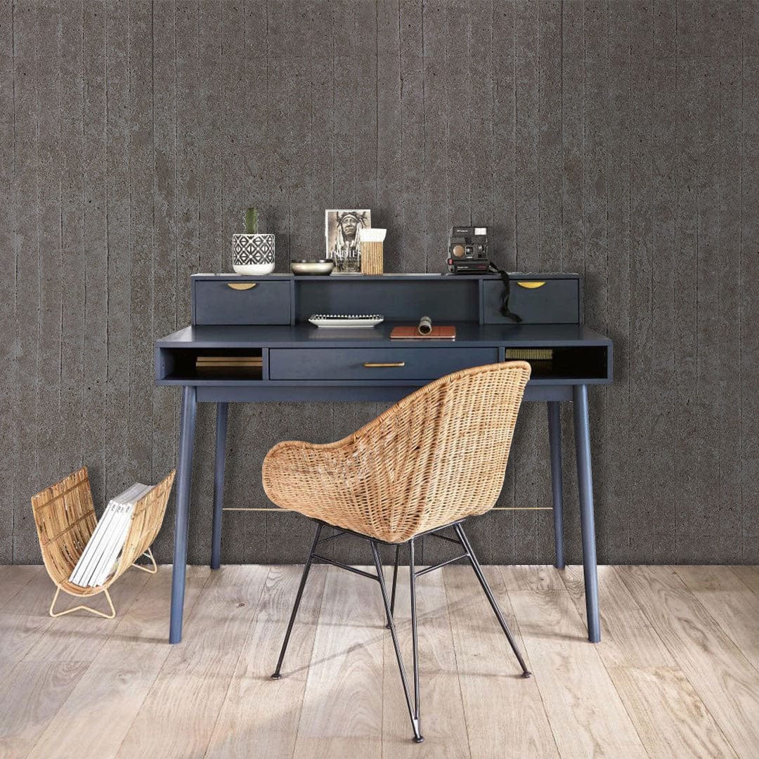 Urban Grey Industrial Concrete Texture Wallpaper complements dark wood desk, wicker chair, modern interior design.