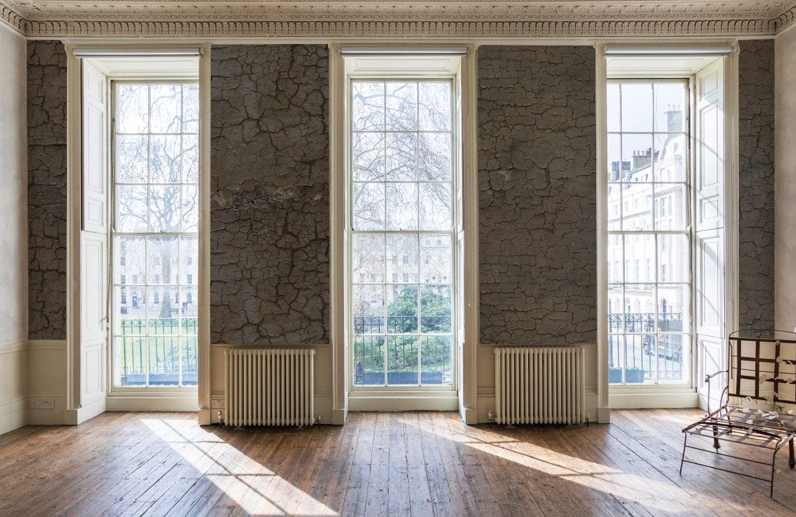 Vintage rustic crackle effect textured grey wallpaper, brown flooring, large windows, classic room setting.