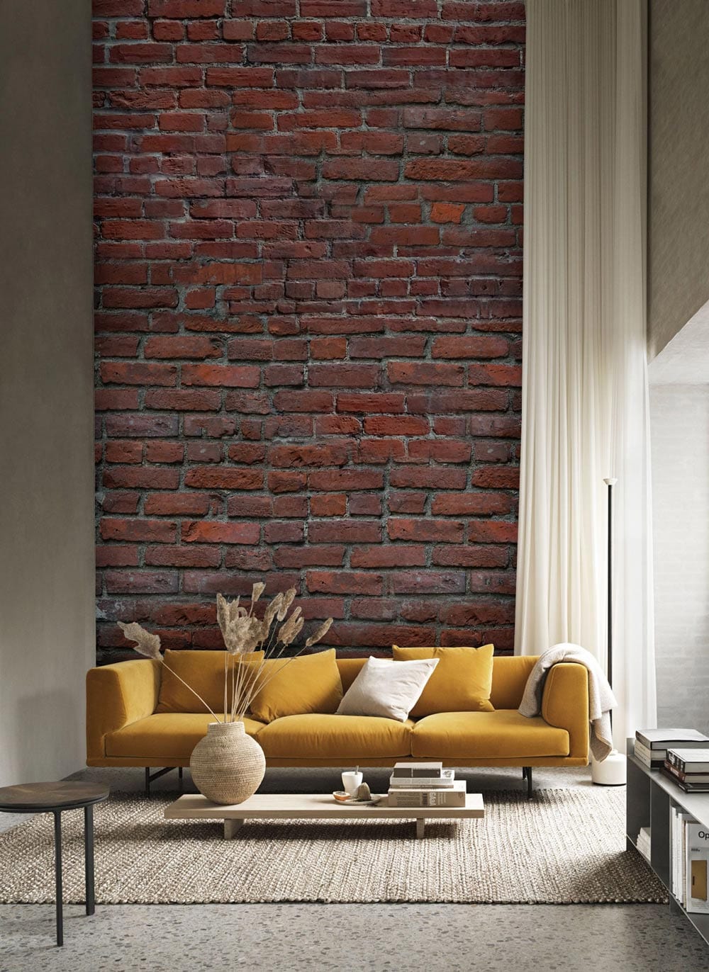 Yellow sofa with rustic red brick wallpaper, light curtains, neutral rug, industrial-style living room decor.