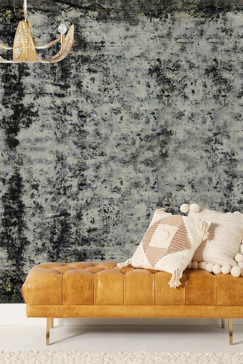 Industrial grey distressed texture wallpaper behind beige leather sofa, modern chandelier, soft rug.