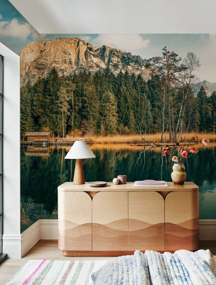 Serene mountain lake mural in earthy tones, wooden sideboard, contemporary decor, cosy living room.