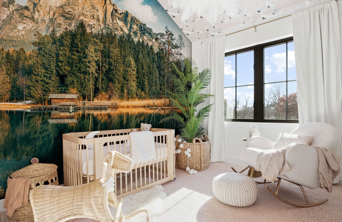 Baby room with serene mountain lake mural wallpaper, earthy tones, rattan crib, cream rocking chair.
