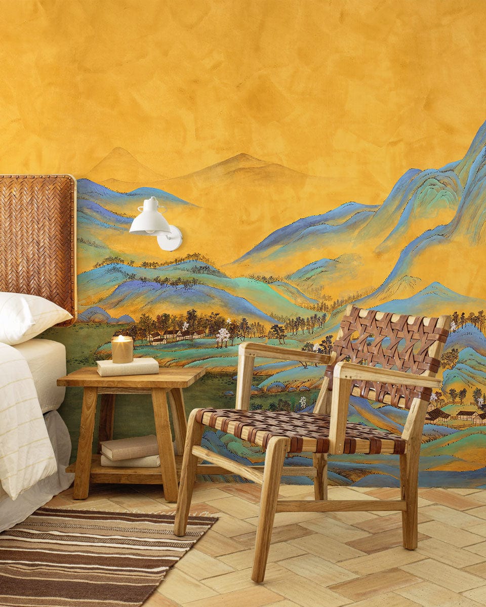 Golden Tranquility mural with woven chair, bedside table, and light wood herringbone flooring in bedroom.