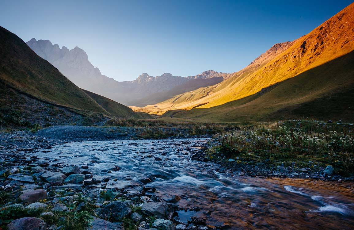 Sublime Mountain Valley Landscape Mural Wallpaper in Warm Sunset Tones