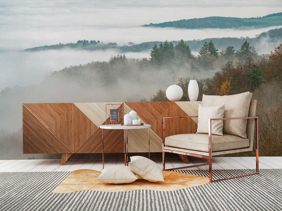 Misty Autumn Forest mural wallpaper; tranquil mountain scenery; modern wooden sideboard; beige armchair; striped rug.