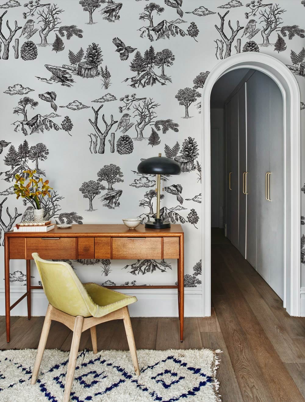 Vintage Woodland Toile Wallpaper on feature wall, wooden desk, green chair, hardwood flooring in study.