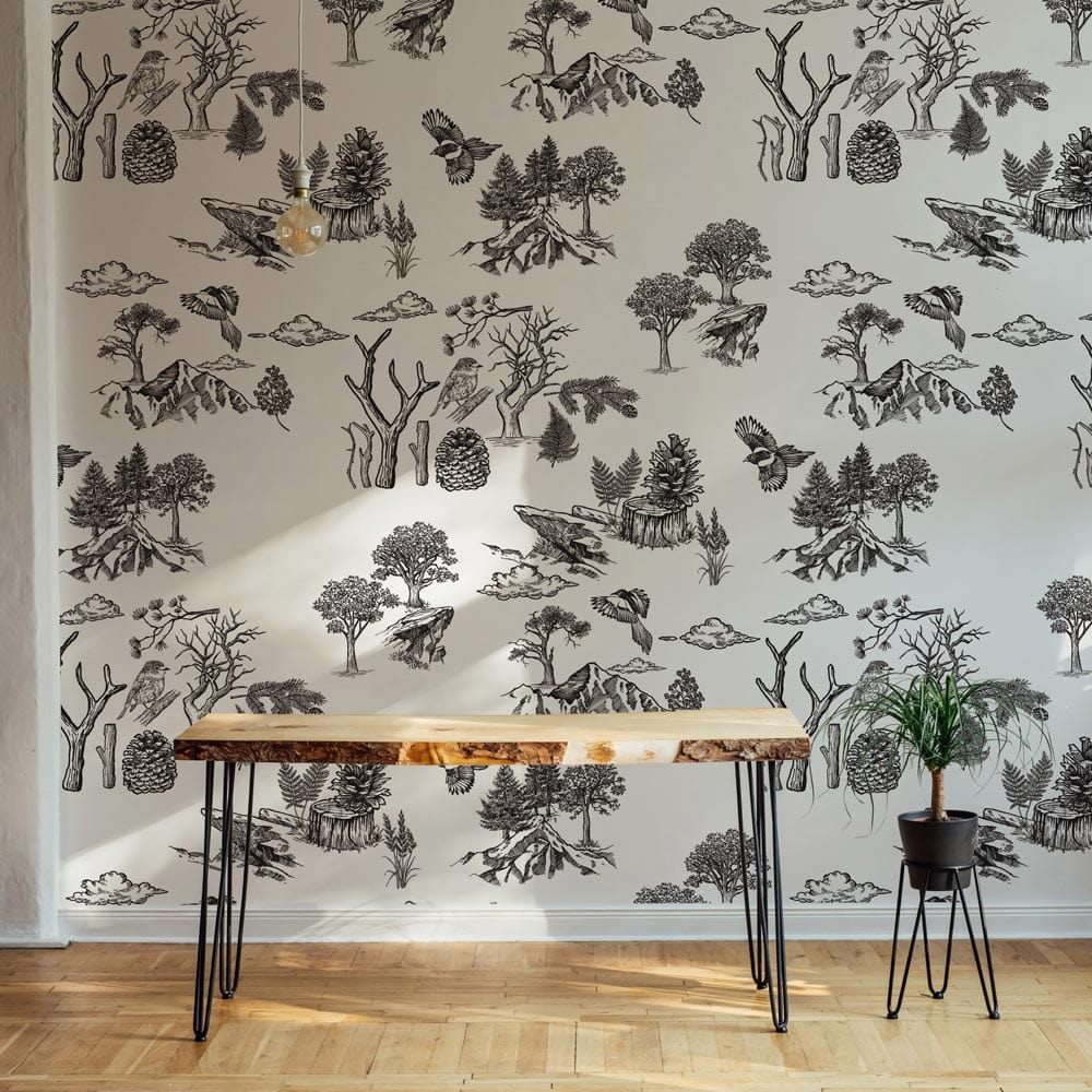 Vintage Woodland Toile wallpaper, monochrome nature scene, light wood table, plant on light parquet flooring.